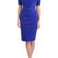 brunette model wearing diva catwalk wessex pencil velvet dress with off shoulder open neckline and overlapping front and short sleeves in blue colour front