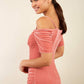 brunette model wearing diva catwalk wessex pencil velvet dress with off shoulder open neckline and overlapping front and short sleeves in pink colour front