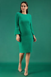 A brunette model is wearing a velvet long bell sleeve pencil dress maternity style in green colour front 