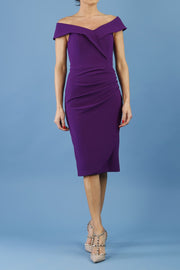 brunette model wearing diva catwalk evening pencil skirt dress sleeveless with lowered neckline and pleating on side in passion purple colour front