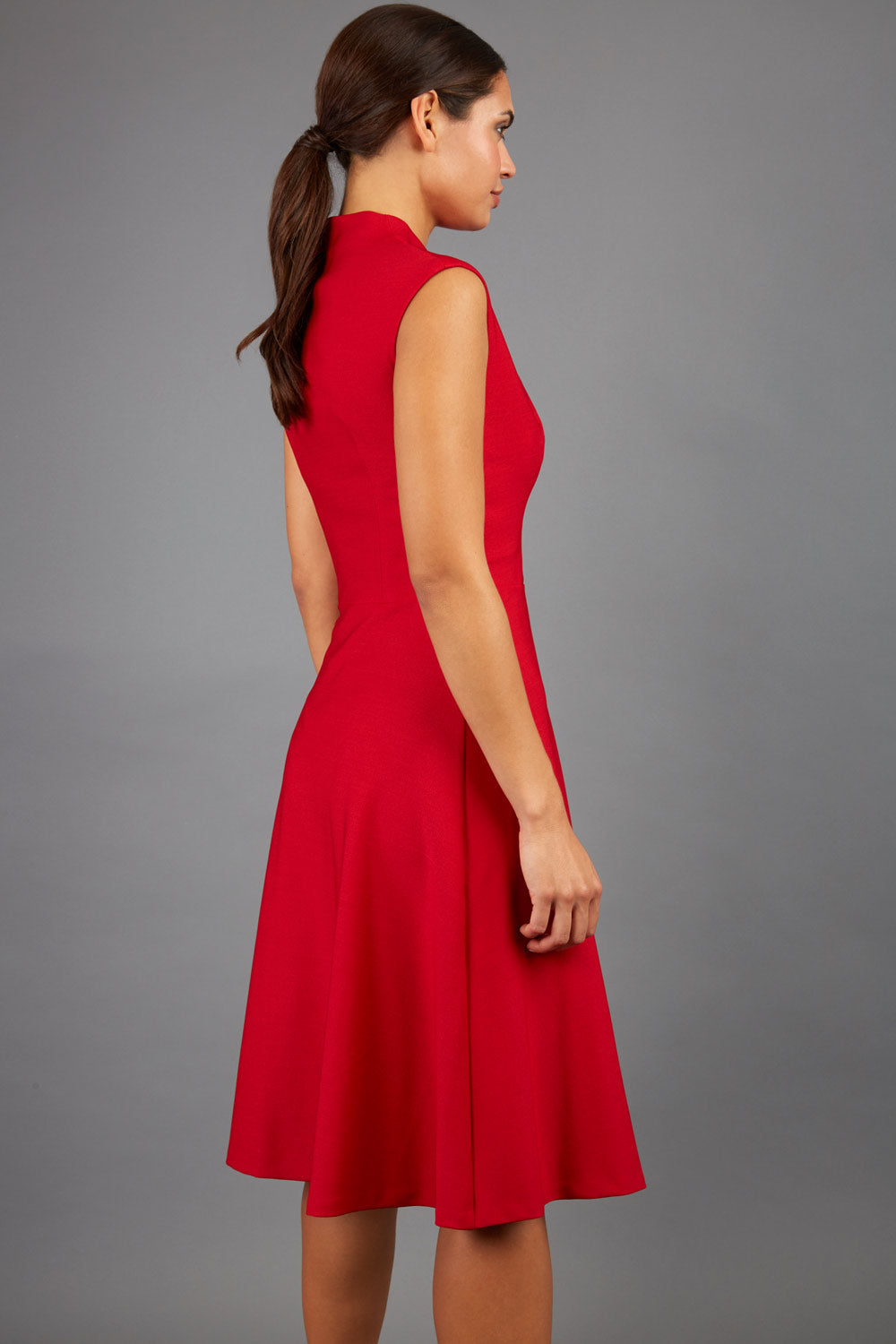 Brunette Model is wearing a sleeveless swing high neck dress with high neck in red by Diva Catwalk back