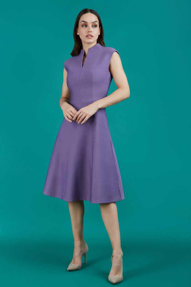 Brunette Model is wearing a sleeveless swing high neck dress with high neck in dusky lilac by Diva Catwalk front