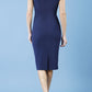 model is wearing diva catwalk polly cap sleeve pencil dress with rounded neckline at the front and deep lowered rounded cutout at the back in navy blue back