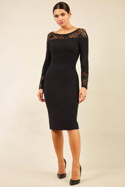 brunette model wearing diva catwalk black lace pencil dress with long sleeves and rounded lace neckline with the lace covering shoulders front