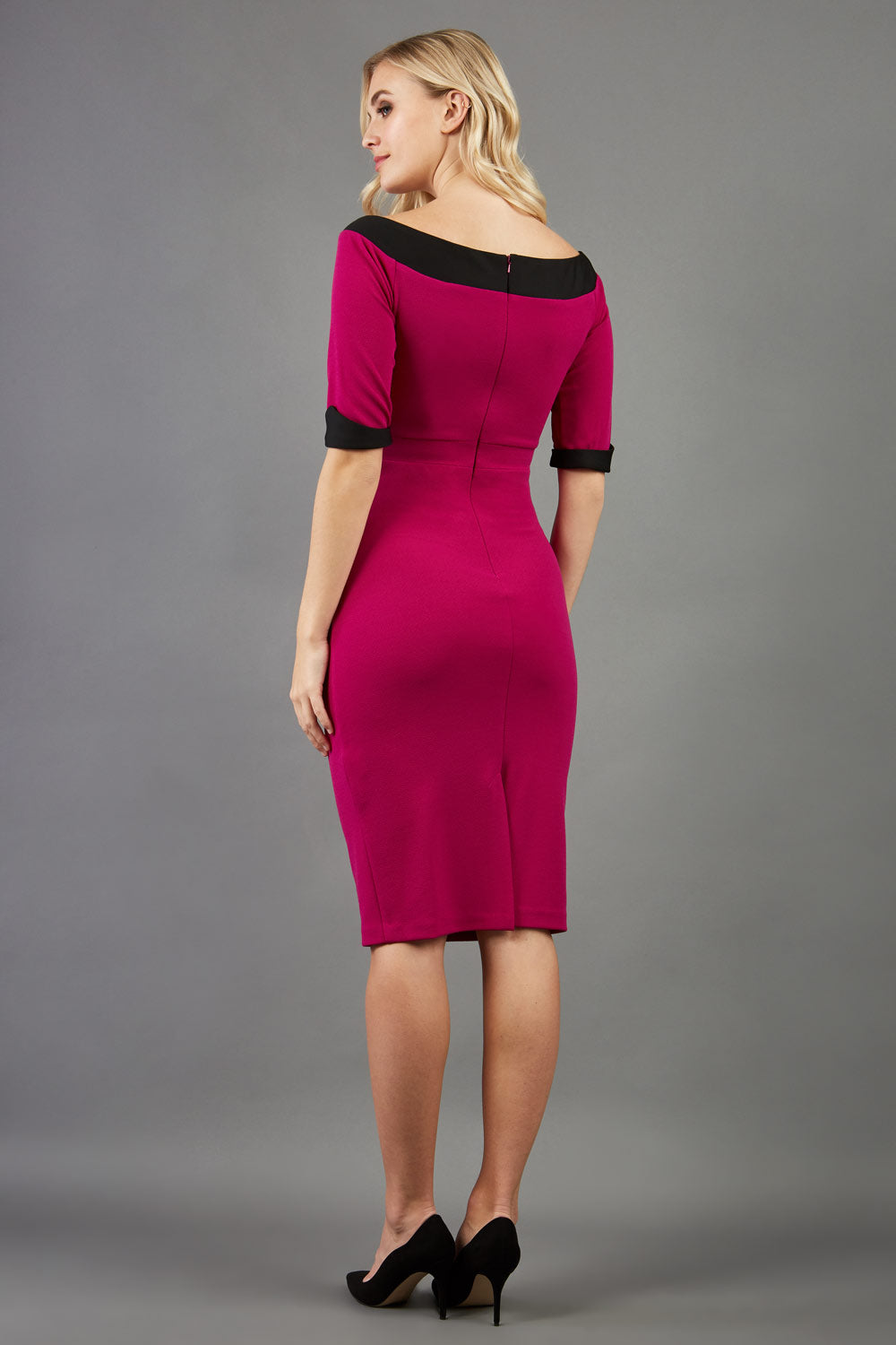 blonde model is wearing diva catwalk fellini sweetheart neckline fitted pencil dress with sleeves with cuff in colour pink with black contrasting detail back