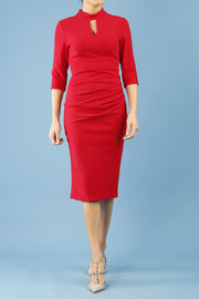 model is wearing diva catwalk pinhoe pencil dress with sleeved and high neckline with a keyhole detail in the middle and pleating across the tummy area in true red front