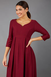Brunette Model is wearing 3/4 sleeve sweetheart neckline  swing burgundy dress