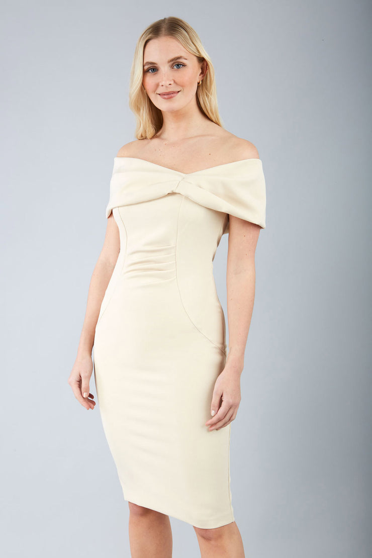 blonde model is wearing diva catwalk mariposa pencil dress with Detailed Bardot neckline with fold-over detail and pleated at waist area in sandshell beige front
