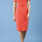 blonde model is wearing diva catwalk mariposa pencil dress with Detailed Bardot neckline with fold-over detail and pleated at waist area in grenadine orange front