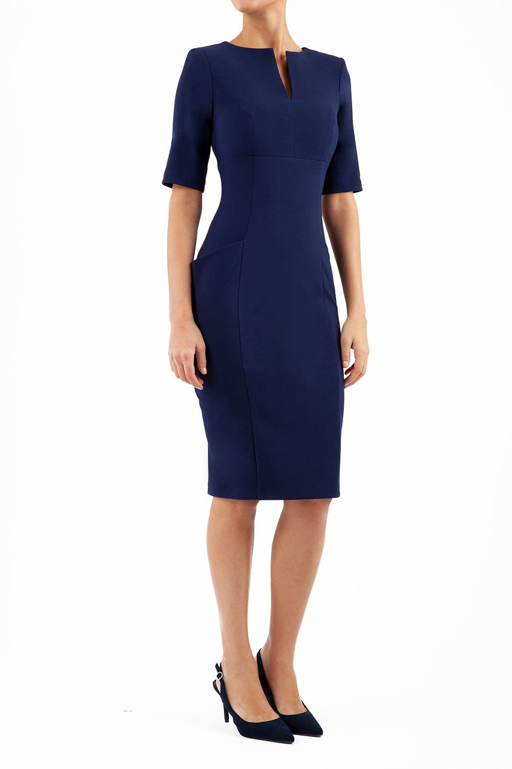 Model wearing Diva catwalk Derwent Pencil skirt dress with shoulder pads and short sleeves and pockets on both sides and empire waistline in navy blue front