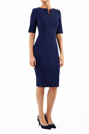 Model wearing Diva catwalk Derwent Pencil skirt dress with shoulder pads and short sleeves and pockets on both sides and empire waistline in navy blue front