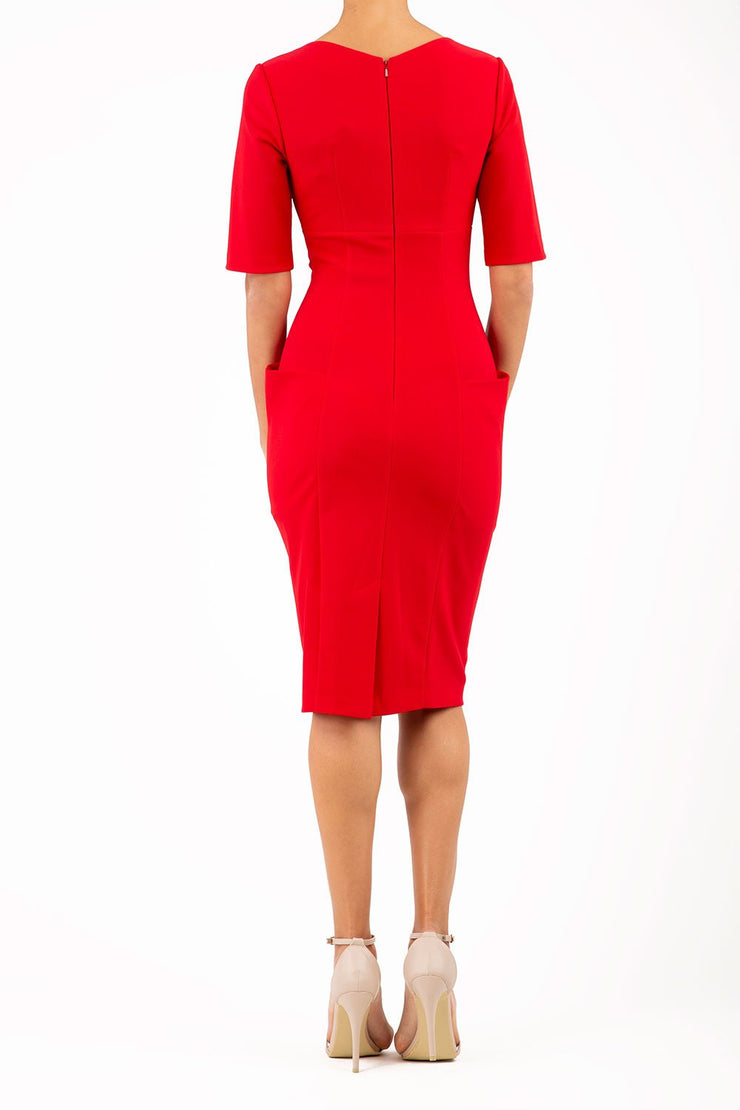 Model wearing Diva catwalk Derwent Pencil skirt dress with shoulder pads and short sleeves and pockets on both sides and empire waistline in true red back