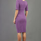Model wearing Diva catwalk Derwent Pencil skirt dress with shoulder pads and short sleeves and pockets on both sides and empire waistline in purple heart back