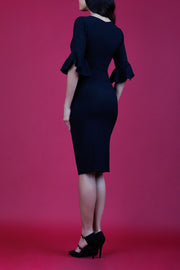 brunette model is wearing diva catwalk hollie pencil dress with frilled flute sleeve and low v-neck cut in black back