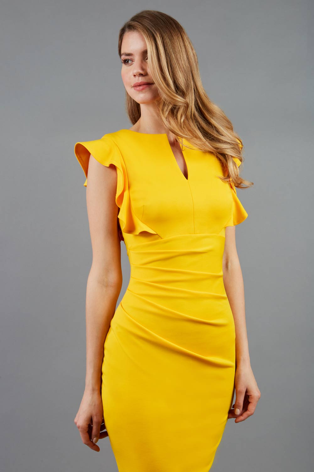 model wearing diva catwalk Bodiam Bodycon Pencil Dress with frill sleeves in knee length and pleating across the tummy in yellow front
