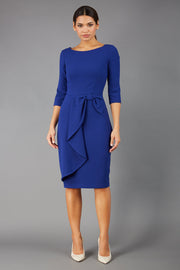 model is wearing diva catwalk jacky dress with rounded neckline 3/4 sleeve and bow detail on the waist in oxford blue front 