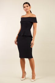 brunette model wearing diva catwalk peplum pencil skirt dress in black colour off shoulder bardot neckline front