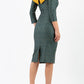 A brunette model is wearing a bi stretch pencil print mustard green dress by diva catwalk back image