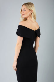 odel wearing diva catwalk vegas calf length black midaxi dress with wide bardot neckline and open shoulders with a large opening at the front of the skirt with pleating coming down long skirt back