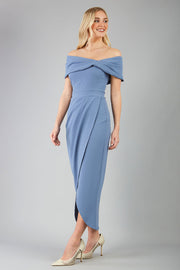 odel wearing diva catwalk vegas calf length stone blue midaxi dress with wide bardot neckline and open shoulders with a large opening at the front of the skirt with pleating coming down long skirt front