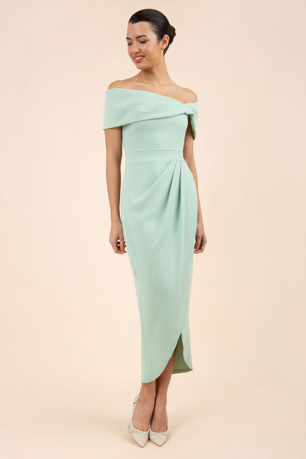 brunette model wearing diva catwalk vegas calf length pale green midaxi dress with wide bardot neckline and open shoulders with a large opening at the front of the skirt with pleating coming down long skirt front
