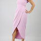 model wearing diva catwalk vegas calf length dawn pale pink midaxi dress with wide bardot neckline and open shoulders with a large opening at the front of the skirt with pleating coming down long skirt front