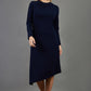 blonde model is wearing diva catwalk dartington asymmetric skirt midaxi long sleeve dress with rounded pleated neckline a-line style in navy blue front