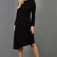 blonde model is wearing diva catwalk dartington asymmetric skirt midaxi long sleeve dress with rounded pleated neckline a-line style in black front
