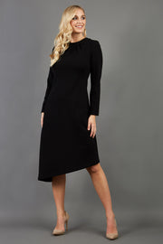 blonde model is wearing diva catwalk dartington asymmetric skirt midaxi long sleeve dress with rounded pleated neckline a-line style in black front