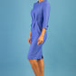 blonde model is wearing diva catwalk logan round neck sleeved pencil dress with side arrow pleating detail in thistle blue side