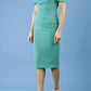 Model wearing the Diva Atlas Pencil dress with round neckline short sleeved dress with small cutouts on the shoulders in emerald green front