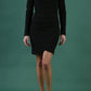 Image of model wearing a long sleeved pleased Mini Pencil Dress from Diva Catwalk in Black in high heal shoes and a green background
