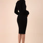 Blonde model wearing Diva Catwalk Praktica long puffed bishop sleeves knee length empire line pencil dress with round neckline with a slit cut in the middle in Black back