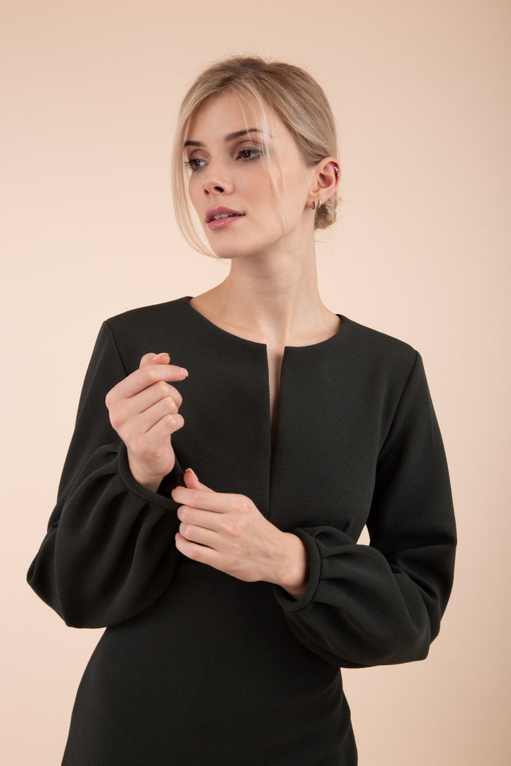 Blonde model wearing Diva Catwalk Praktica long puffed bishop sleeves knee length empire line pencil dress with round neckline with a slit cut in the middle in Dark Green front