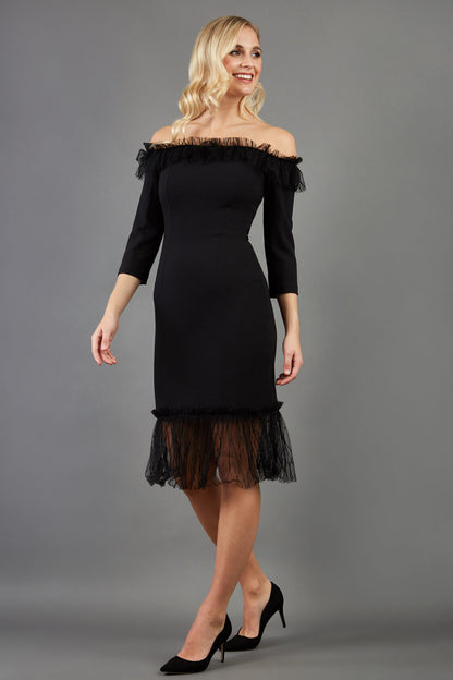 Brunette Model wearing Diva Catwalk Lyrical Pencil Knee length three quarter sleeve off-shoulder Bardot neckline Dress with lace detail around the bottom of the skirt in Black front