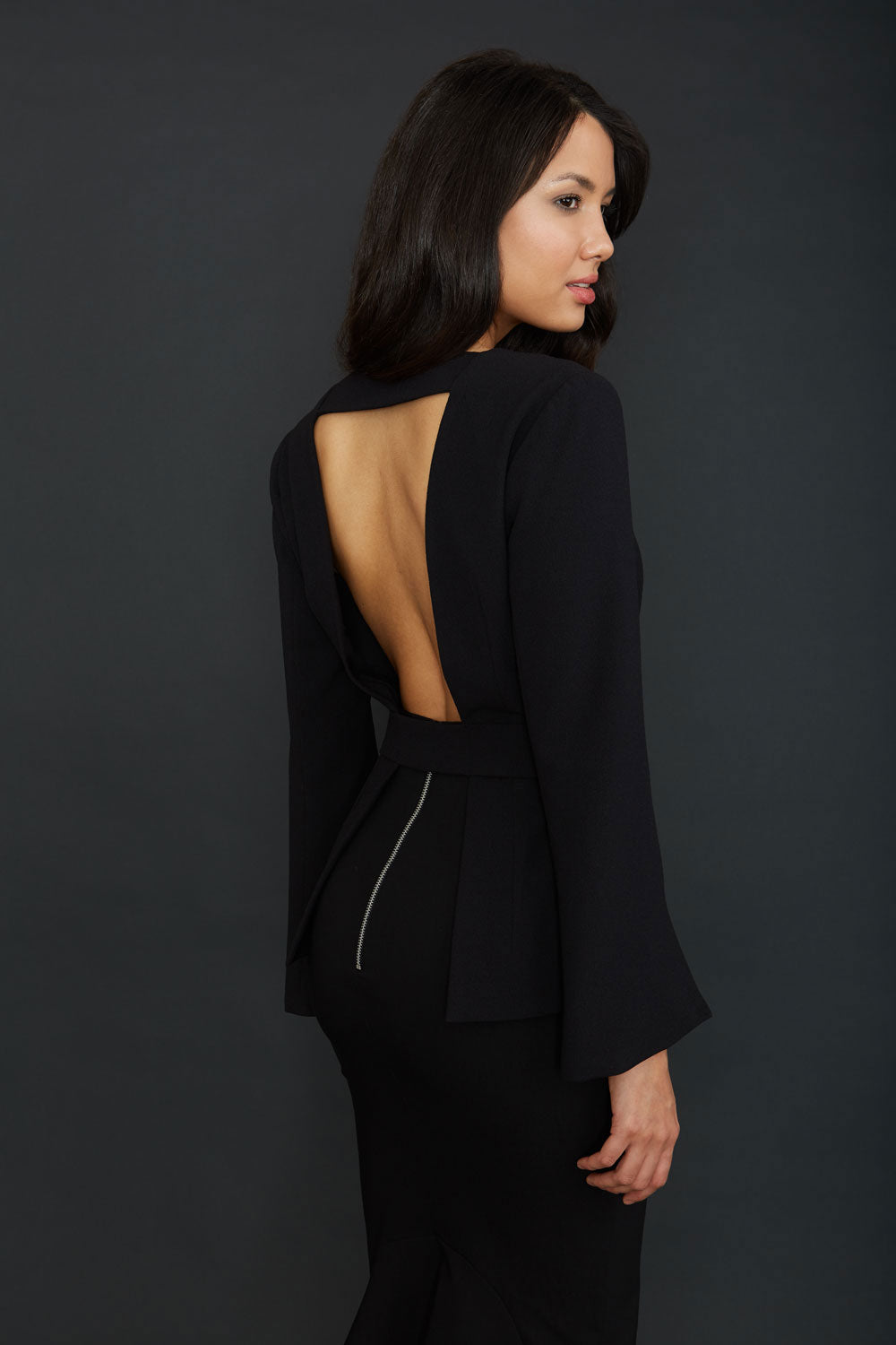 Brunette Model wearing Diva Catwalk Attimo Full length sleeve cut out back Jacket with belted waistline and sleeves with slits from elbow in Black back