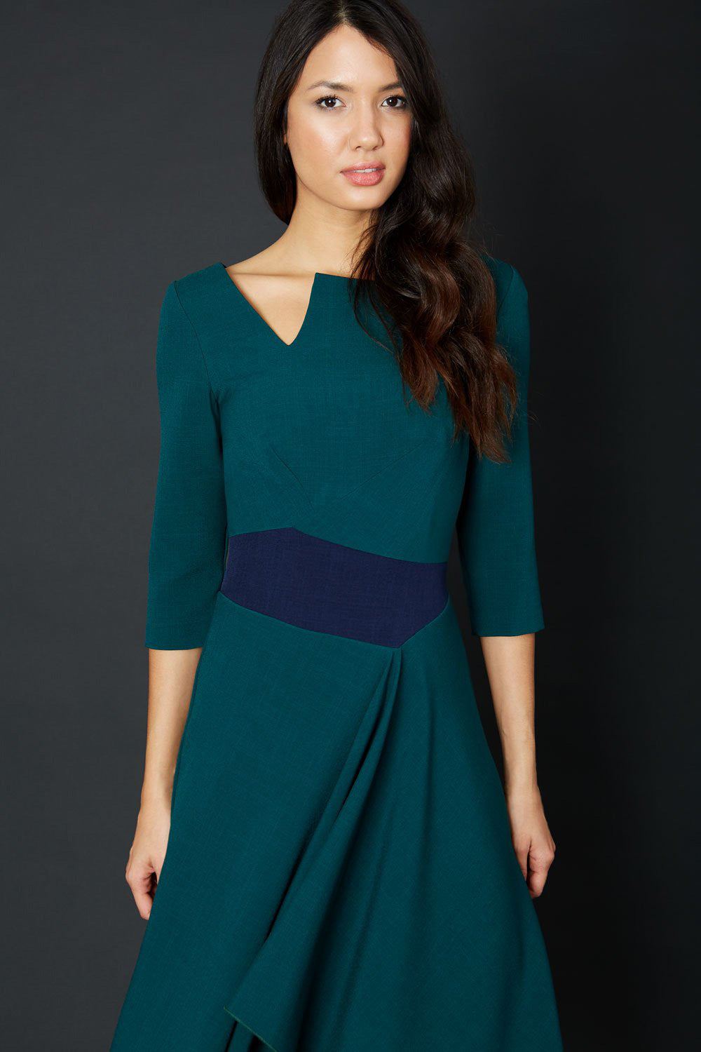 Blonde Model wearing Diva Catwalk Pinto Contrast Swing Dress with asymmetric skirt and asymmetric neckline with three quarter sleeve in Forest Green front