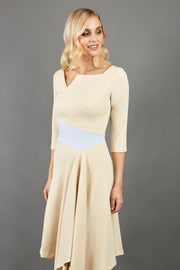 Blonde Model wearing Diva Catwalk Pinto Contrast swing a-line skirt Dress with asymmetric skirt and asymmetric neckline with three quarter sleeve in Sandshell Beige with Celestial pale blue front