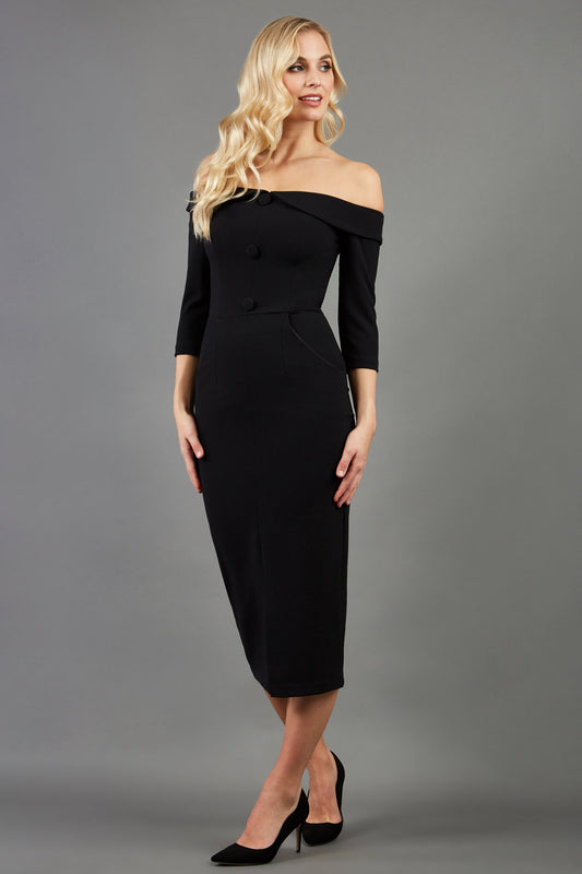 blonde model is wearing three quarter fitted dress off-shoulder with bardot neckline and buttons to front with pockets and vent on a skirt in black front