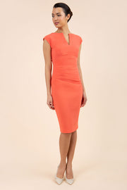 brunette model wearing diva catwalk lydia sleeveless pencil flattering fitted plain dress with split neckline and pleating across the body sea coral front
