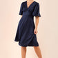 model wearing diva catwalk cambrian satin swing dress with bell short sleeve wide asymmetric waistband and pleating under bust and low v-neckline in navy front