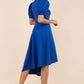 brunette model wearing diva catwalk ola swing dress with puffed oversized sleeves and asymmetric swing skirt with rounded high neck in blue back