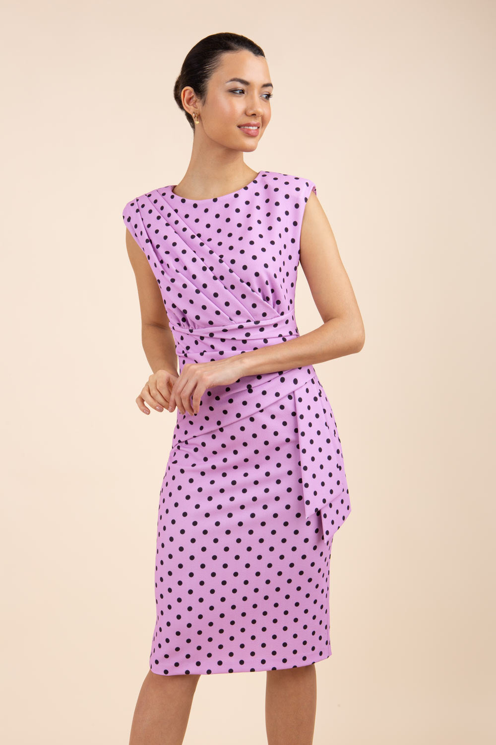 Brunette model wearing Diva Catwalk Perry Polka Dot Pencil Sleeveless Dress with tie detail on a side and rounded neckline in pink front