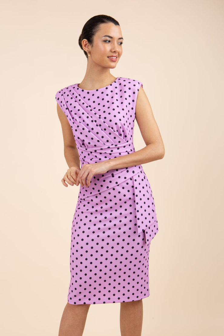 Brunette model wearing Diva Catwalk Perry Polka Dot Pencil Sleeveless Dress with tie detail on a side and rounded neckline in pink front