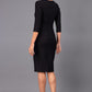 Model wearing Diva catwalk Minette dress in black with three quarter sleeve figure fitted pencil dress back image