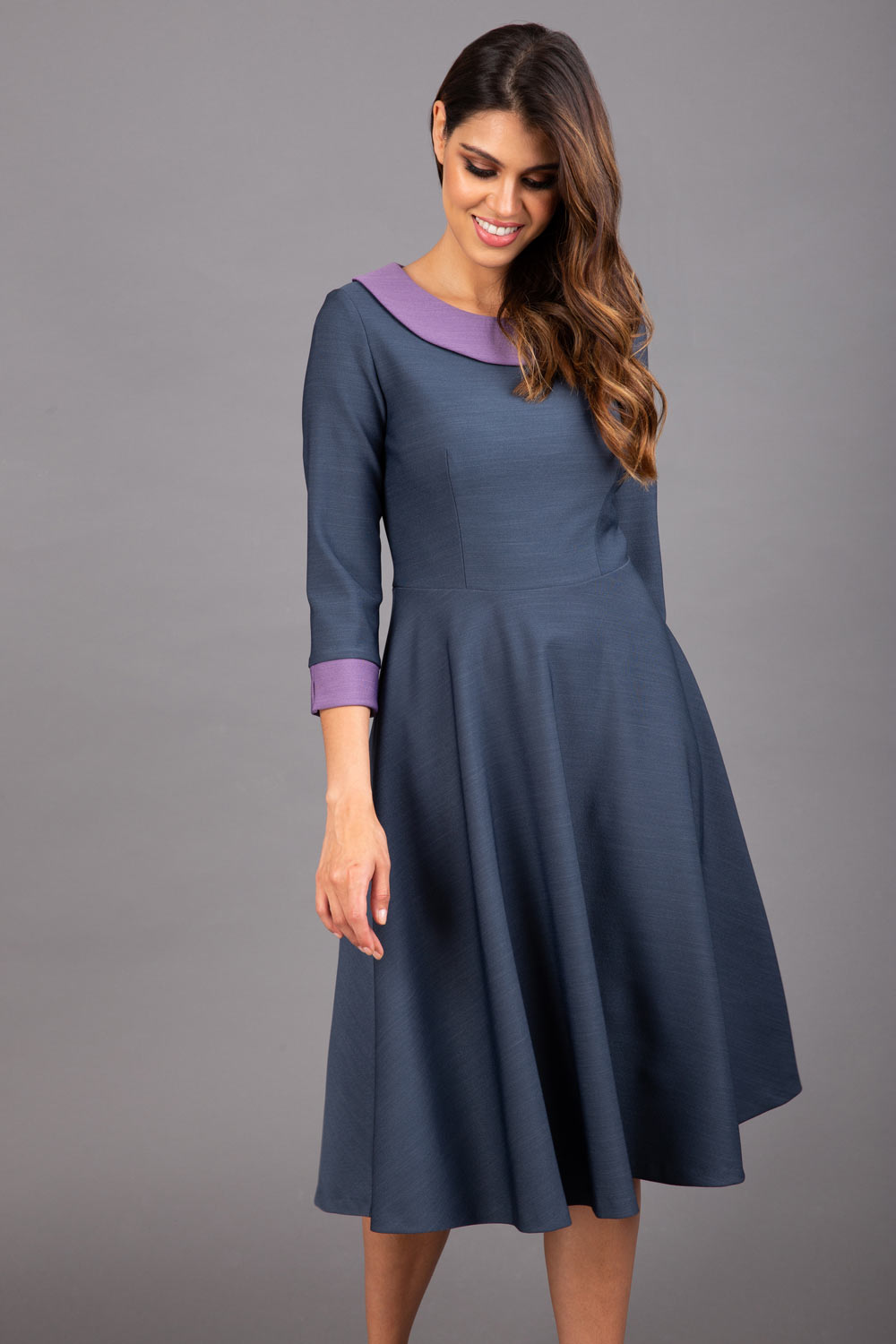 Model wearing Diva catwalk Coralia swing dress in slate grey/ lilac with three quarter sleeve figure fitted front image