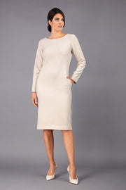 brunette model wearing diva catwalk cora white pencil dress with long sleeves and rounded neckline with pockets in colour cream on side front