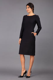 brunette model wearing diva catwalk cora white pencil dress with long sleeves and rounded neckline with pockets in colour black on side front