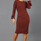 brunette model wearing diva catwalk fitted dress with sleeves called Alma Pencil-skirt dress in colour mahogany brown with bow detail on sleeves front