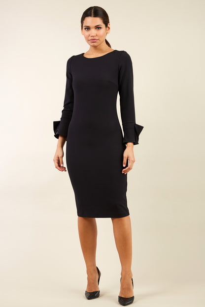 brunette model wearing diva catwalk fitted dress with sleeves called Alma Pencil-skirt dress in colour black with bow detail on sleeves front